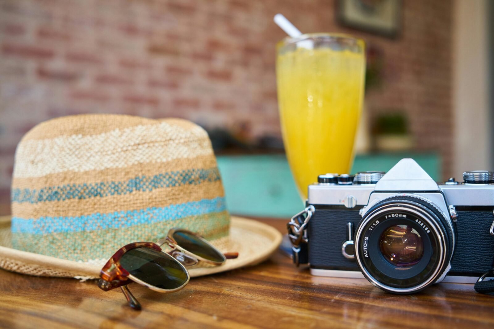 How to Find the Perfect Vacation Destination A stylish scene showcasing a vintage camera, hat, and orange juice, evoking summer travel vibes.